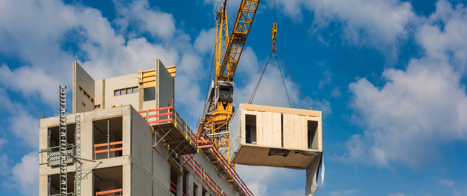 Crane lifting a wooden building module to its position in the structure