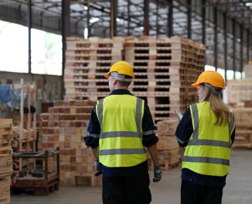 Back view of two construction workers walking through a warehouse